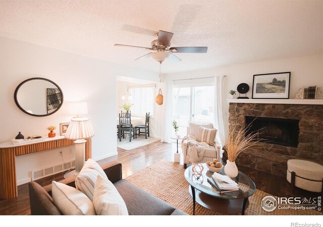 3025 Regatta Ln Unit 3, Fort Collins, CO 80525 - living area with a ceiling fan, wood finished floors, a stone fireplace, and a textured ceiling