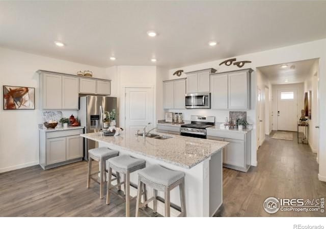 1885 Mount Monroe Dr, Berthoud, CO 80513 - kitchen featuring stainless steel appliances, gray cabinetry, a kitchen bar, wood finished floors, and recessed lighting