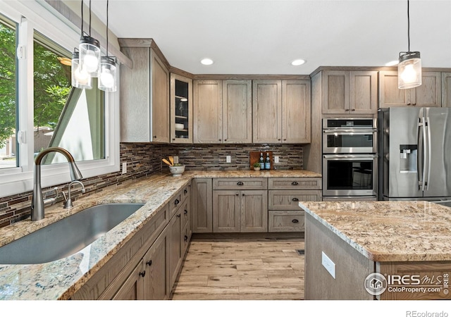 40 Walter Way, Broomfield, CO 80020 - kitchen featuring stainless steel appliances, light wood-style floors, backsplash, glass insert cabinets, and light stone countertops