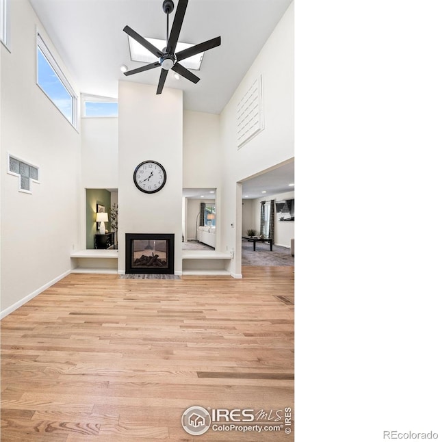 40 Walter Way, Broomfield, CO 80020 - unfurnished living room with a towering ceiling, light wood-style flooring, ceiling fan, and a multi sided fireplace
