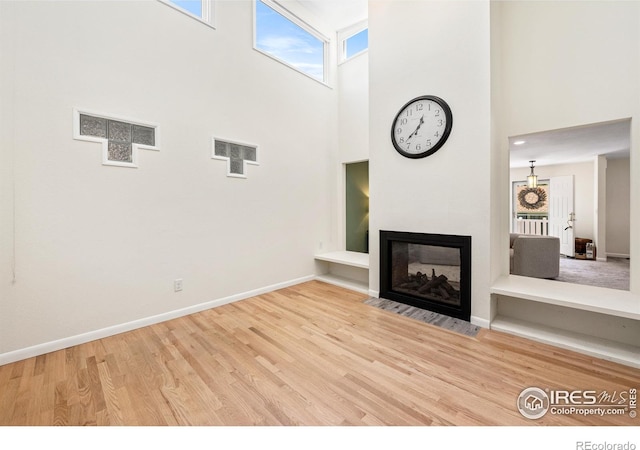 40 Walter Way, Broomfield, CO 80020 - unfurnished living room featuring a towering ceiling, wood finished floors, and a multi sided fireplace