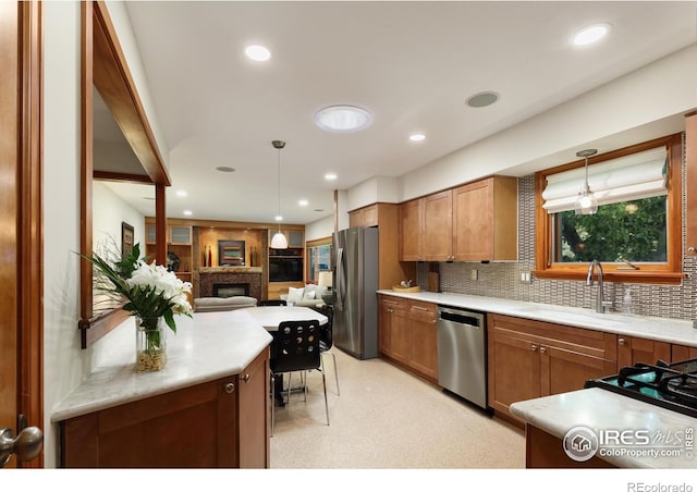 7459 Mount Meeker Rd, Longmont, CO 80503 - kitchen featuring appliances with stainless steel finishes, a fireplace, open floor plan, light countertops, and hanging light fixtures