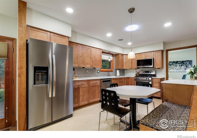 7459 Mount Meeker Rd, Longmont, CO 80503 - kitchen featuring appliances with stainless steel finishes, pendant lighting, decorative backsplash, brown cabinets, and light countertops