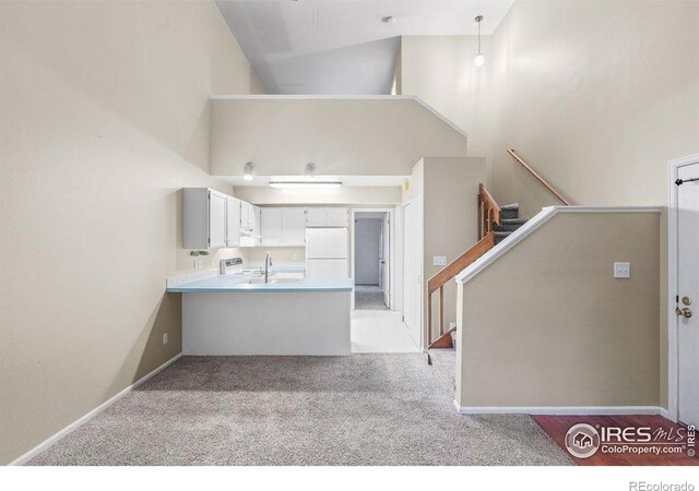 3565 Windmill Dr Unit F-7, Fort Collins, CO 80526 - kitchen with freestanding refrigerator, a high ceiling, a peninsula, light colored carpet, and light countertops