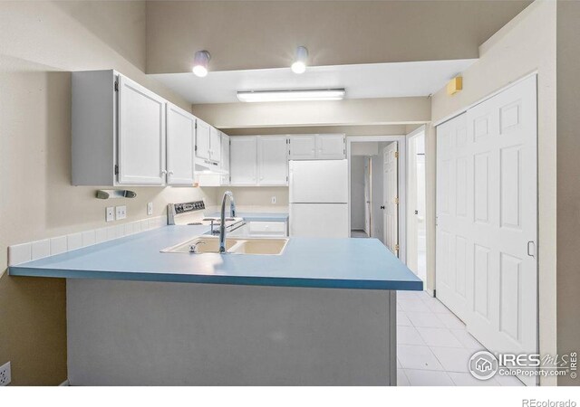 3565 Windmill Dr Unit F-7, Fort Collins, CO 80526 - kitchen featuring freestanding refrigerator, under cabinet range hood, a peninsula, light countertops, and white cabinetry