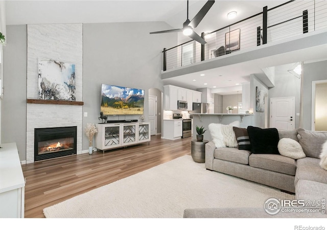 641 Babine Ct, Windsor, CO 80550 - living room with light wood-style floors, ceiling fan, high vaulted ceiling, and a large fireplace