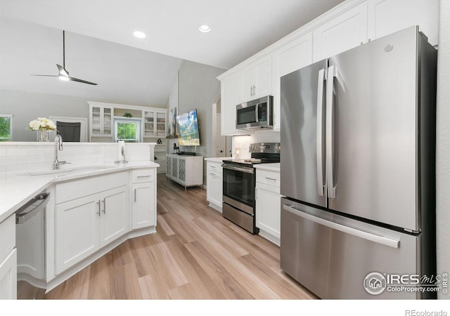 641 Babine Ct, Windsor, CO 80550 - kitchen with appliances with stainless steel finishes, light wood finished floors, a ceiling fan, white cabinets, and backsplash