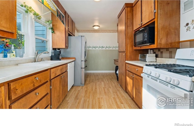 1817 15th Ave, Greeley, CO 80631 - kitchen with white appliances, light wood-type flooring, brown cabinetry, and light countertops