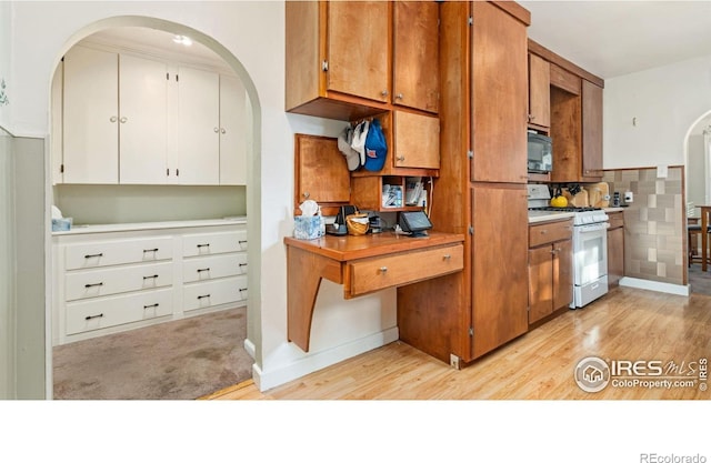 1817 15th Ave, Greeley, CO 80631 - kitchen featuring white gas range oven, black microwave, arched walkways, and light wood finished floors