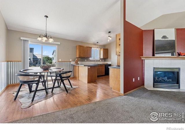 2217 Waylon Dr, Johnstown, CO 80534 - dining space with vaulted ceiling, a chandelier, a tile fireplace, light wood-style flooring, and light carpet