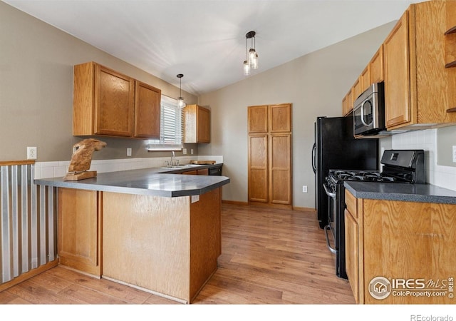 2217 Waylon Dr, Johnstown, CO 80534 - kitchen with black gas stove, stainless steel microwave, lofted ceiling, a peninsula, and light wood-type flooring