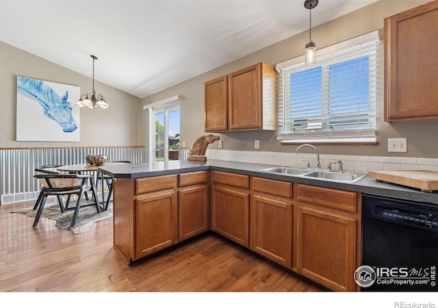 2217 Waylon Dr, Johnstown, CO 80534 - kitchen with dishwasher, lofted ceiling, a peninsula, brown cabinetry, and light wood-style flooring