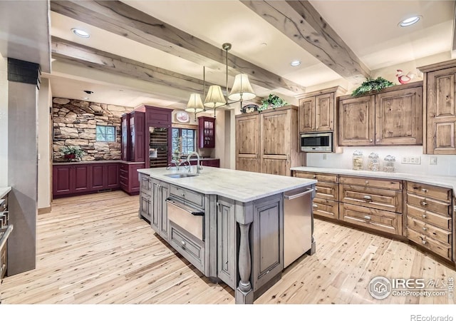 8576 Niwot Meadow Farm Rd, Niwot, CO 80503 - kitchen with a warming drawer, appliances with stainless steel finishes, light wood finished floors, beam ceiling, and an island with sink