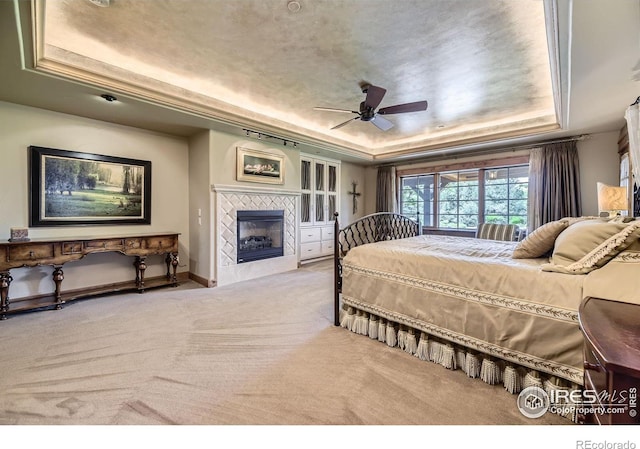 8576 Niwot Meadow Farm Rd, Niwot, CO 80503 - bedroom with a tray ceiling, carpet flooring, a fireplace, and a ceiling fan