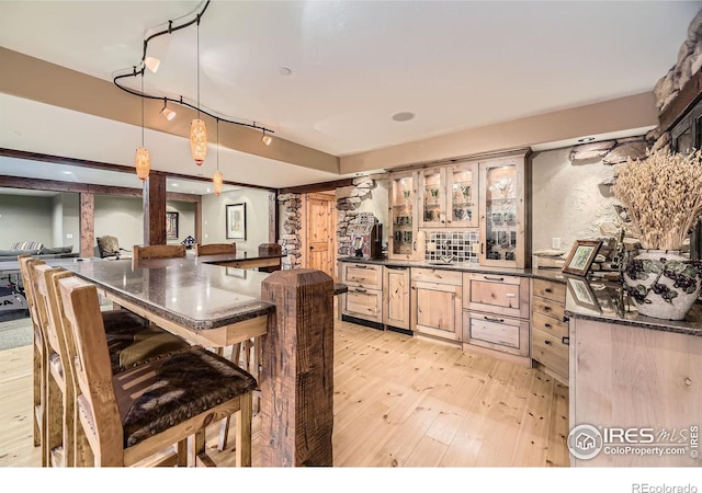 8576 Niwot Meadow Farm Rd, Niwot, CO 80503 - kitchen featuring light wood finished floors, a breakfast bar, glass insert cabinets, hanging light fixtures, and dark stone counters