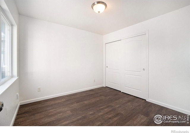 702 Cairnes Dr Unit B4, Fort Collins, CO 80524 - unfurnished bedroom featuring dark wood finished floors, multiple windows, and a closet
