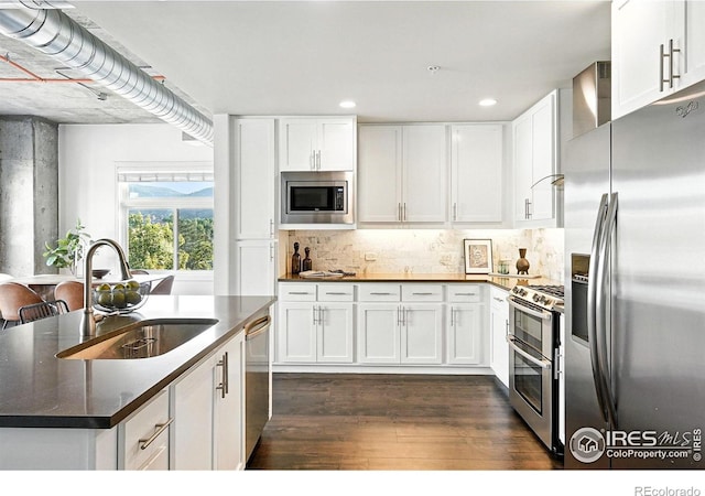 3401 Arapahoe Ave Unit 420, Boulder, CO 80303 - kitchen featuring appliances with stainless steel finishes, dark countertops, dark wood-style floors, white cabinets, and recessed lighting