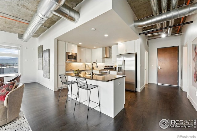 3401 Arapahoe Ave Unit 420, Boulder, CO 80303 - kitchen with appliances with stainless steel finishes, wall chimney exhaust hood, dark wood-style floors, white cabinetry, and recessed lighting