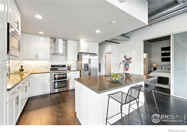 3401 Arapahoe Ave Unit 420, Boulder, CO 80303 - kitchen with stainless steel appliances, wall chimney range hood, dark wood finished floors, a kitchen breakfast bar, and white cabinetry