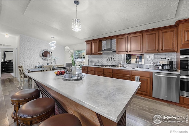 2036 1st Ave Unit 437, Greeley, CO 80631 - kitchen featuring appliances with stainless steel finishes, light wood-style flooring, a kitchen breakfast bar, wall chimney exhaust hood, and backsplash