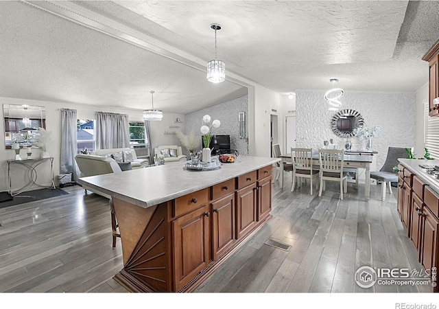 2036 1st Ave Unit 437, Greeley, CO 80631 - kitchen with a textured ceiling, dark wood-style flooring, light countertops, decorative light fixtures, and brown cabinetry