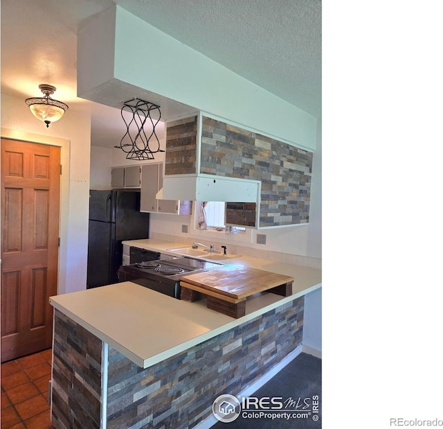 1550 W 28th St Unit 1, Loveland, CO 80538 - kitchen featuring a peninsula, range with electric stovetop, light countertops, freestanding refrigerator, and tile patterned flooring
