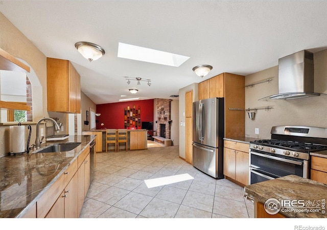 2513 Lanyon Dr, Longmont, CO 80503 - kitchen featuring stainless steel appliances, wall chimney range hood, a skylight, dark stone counters, and light tile patterned floors