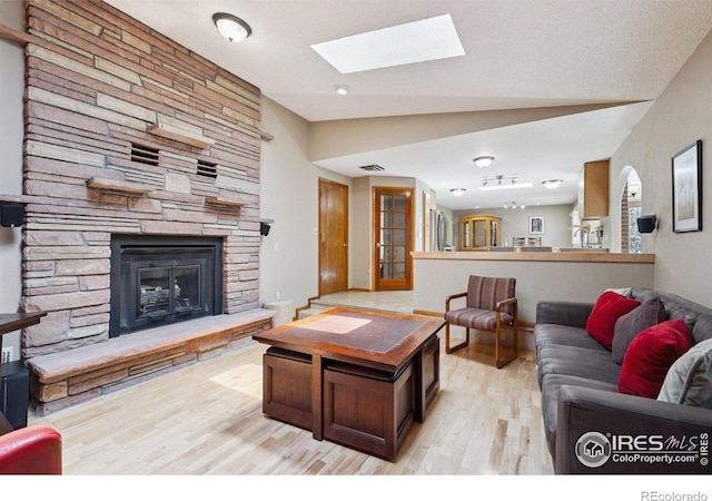 2513 Lanyon Dr, Longmont, CO 80503 - living area with light wood-style floors, vaulted ceiling, a skylight, and a stone fireplace