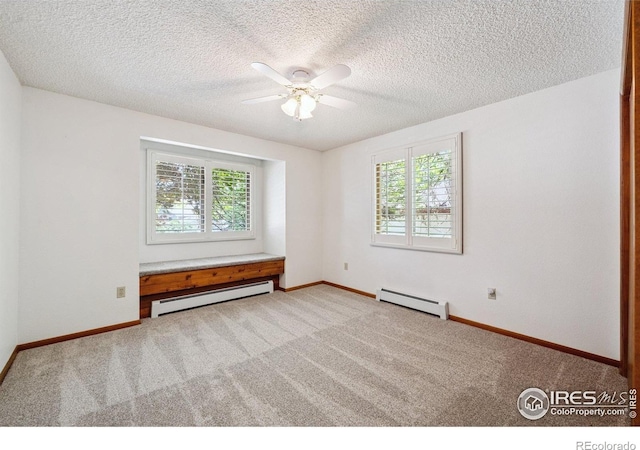2513 Lanyon Dr, Longmont, CO 80503 - carpeted empty room with a baseboard heating unit, healthy amount of natural light, a ceiling fan, and a textured ceiling