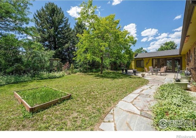 2513 Lanyon Dr, Longmont, CO 80503 - view of grassy yard featuring a garden, a patio area, and french doors