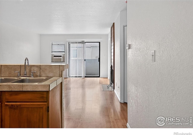 3535 28th St # 202, Boulder, CO 80301 - kitchen featuring a textured wall, wood finished floors, brown cabinetry, a textured ceiling, and cooling unit