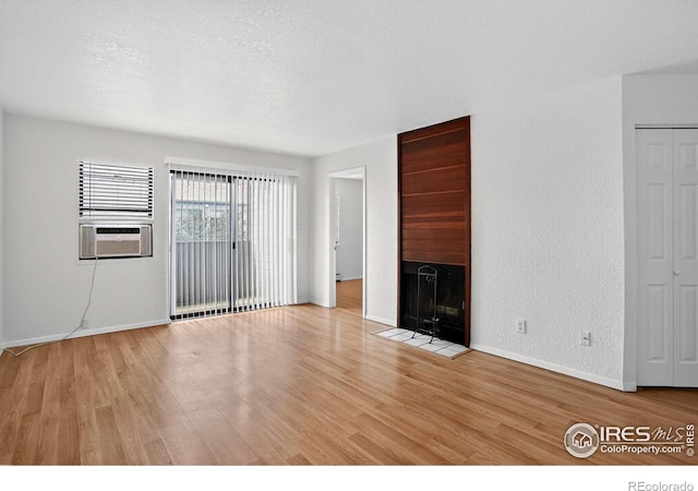 3535 28th St # 202, Boulder, CO 80301 - unfurnished living room featuring light wood-style floors, cooling unit, a fireplace with flush hearth, a textured ceiling, and a textured wall