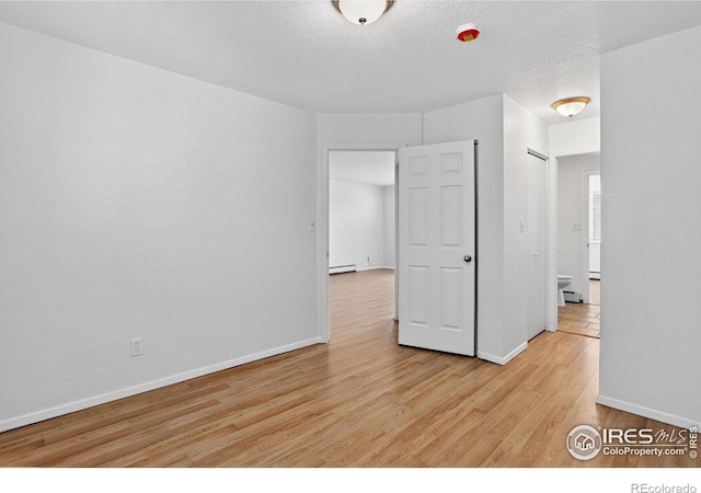 3535 28th St # 202, Boulder, CO 80301 - unfurnished room with a baseboard heating unit, light wood-style flooring, and a textured ceiling
