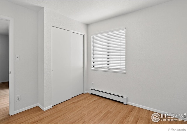 3535 28th St # 202, Boulder, CO 80301 - unfurnished bedroom with baseboard heating, light wood-style floors, and a closet