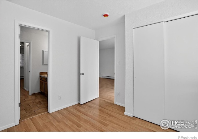 3535 28th St # 202, Boulder, CO 80301 - unfurnished bedroom featuring baseboard heating, light wood finished floors, a closet, and ensuite bath