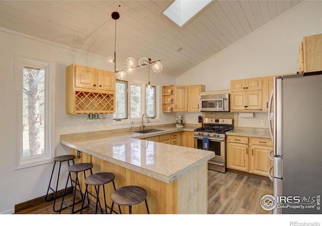 30795 W Ridge Rd, Buena Vista, CO 81211 - kitchen featuring appliances with stainless steel finishes, a peninsula, light brown cabinets, lofted ceiling, and a breakfast bar