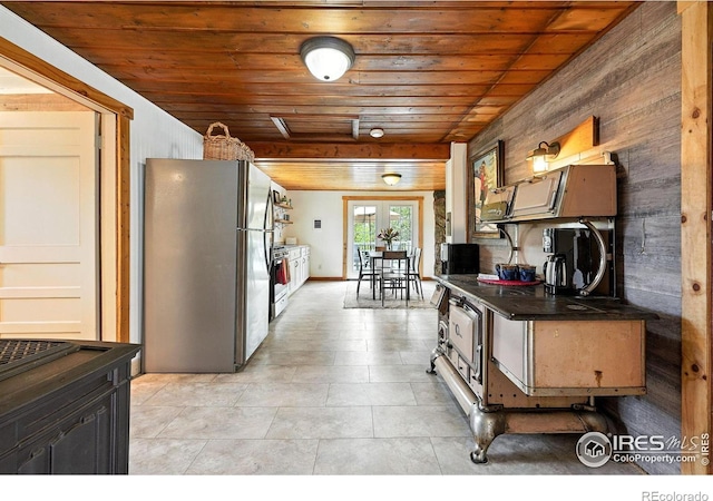 181 County Road 874, Tabernash, CO 80478 - kitchen with freestanding refrigerator, wooden ceiling, dark countertops, wood walls, and light tile patterned flooring