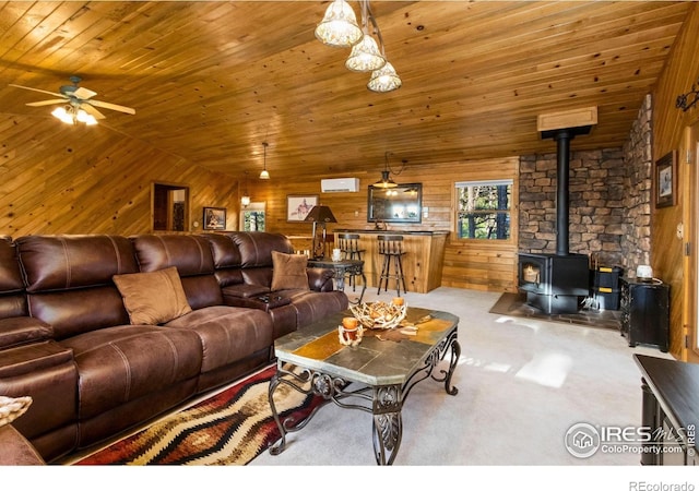 451 Newell Dr, Loveland, CO 80537 - carpeted living area featuring wooden ceiling, wood walls, a wood stove, and a ceiling fan