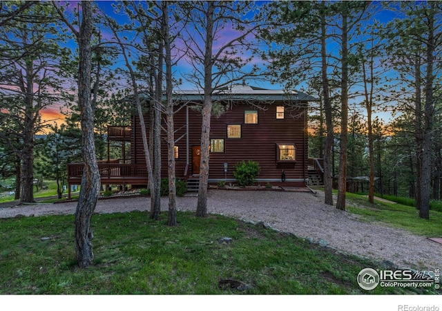 451 Newell Dr, Loveland, CO 80537 - view of front of property with faux log siding, a wooden deck, and a lawn