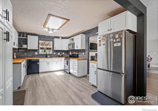 607 42nd Ave, Greeley, CO 80634 - kitchen with appliances with stainless steel finishes, butcher block countertops, light wood-style flooring, decorative backsplash, and a textured ceiling