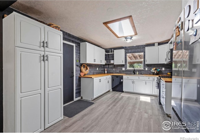 607 42nd Ave, Greeley, CO 80634 - kitchen featuring stainless steel appliances, butcher block counters, a textured ceiling, light wood-style floors, and white cabinetry
