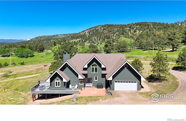 4815 Sugarloaf Rd, Boulder, CO 80302 - view of front of property featuring a forest view, dirt driveway, a chimney, and an attached garage