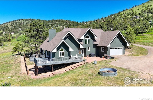 4815 Sugarloaf Rd, Boulder, CO 80302 - chalet / cabin featuring a deck, a chimney, a forest view, dirt driveway, and a front yard