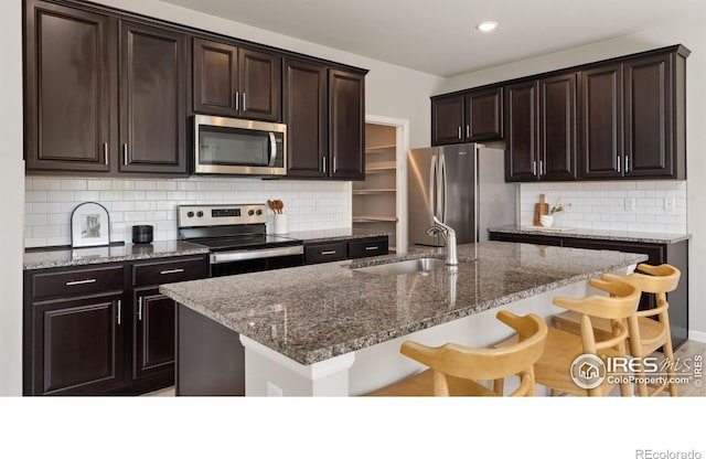 2742 Cooperland Blvd, Berthoud, CO 80513 - kitchen with stainless steel appliances, tasteful backsplash, a breakfast bar, dark stone countertops, and recessed lighting
