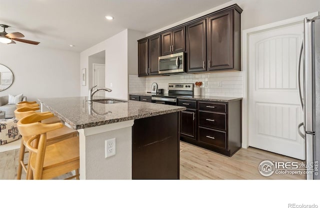 2742 Cooperland Blvd, Berthoud, CO 80513 - kitchen with stainless steel appliances, light wood-type flooring, dark stone counters, decorative backsplash, and recessed lighting