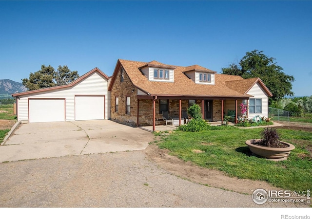 7035 S Boulder Rd, Boulder, CO 80303 - view of front facade with a porch, concrete driveway, an outbuilding, a mountain view, and a shingled roof