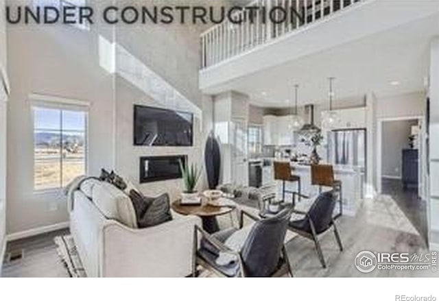 921 Abbott Ln, Fort Collins, CO 80524 - living area featuring a towering ceiling, wood finished floors, and a glass covered fireplace