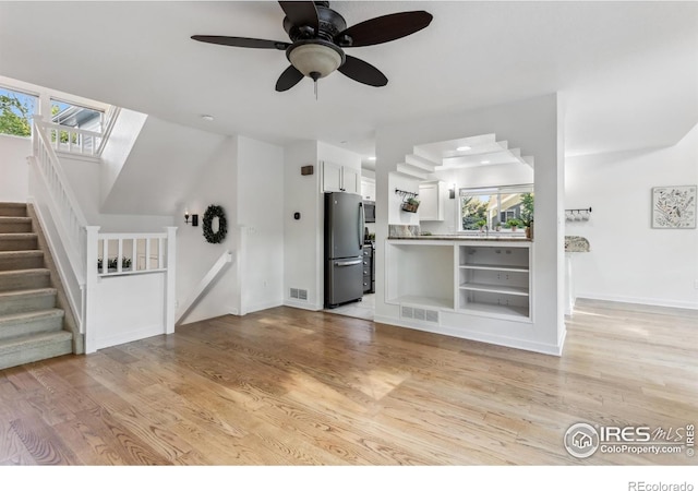 1993 S Fork Dr, Lafayette, CO 80026 - unfurnished living room with stairway, healthy amount of natural light, a ceiling fan, and light wood-style floors