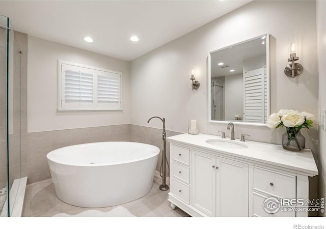 388 Fairfield Ln, Louisville, CO 80027 - bathroom featuring a freestanding tub, vanity, recessed lighting, tile patterned floors, and tile walls