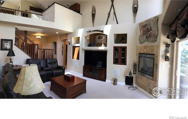 1402 Westfield Dr, Fort Collins, CO 80526 - living room with arched walkways, carpet, stairway, a tiled fireplace, and a high ceiling